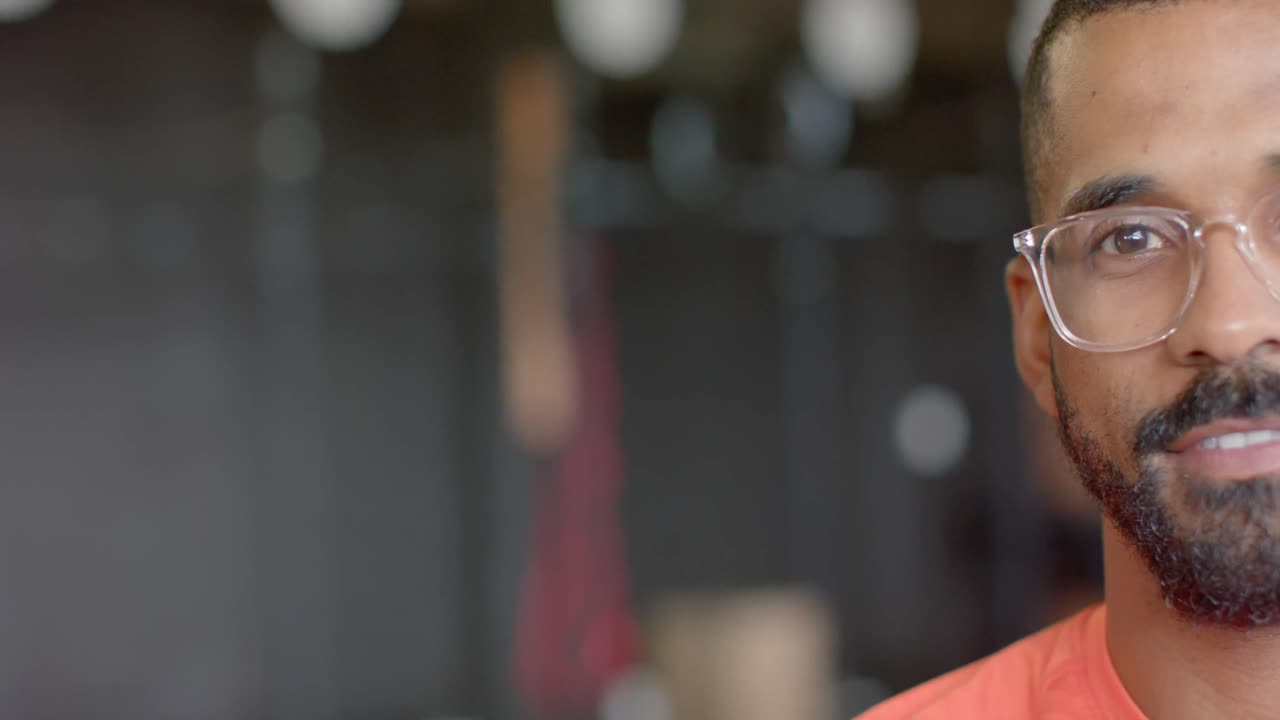 medio retrato de un feliz hombre afroamericano con gafas sonriendo, con espacio para copiar, en cámara lenta.