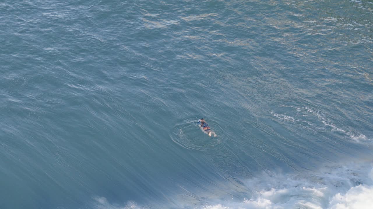 Drone captures surfers navigating waves in Gold Coast, Australia. Bright daylight enhances the dynamic ocean scene