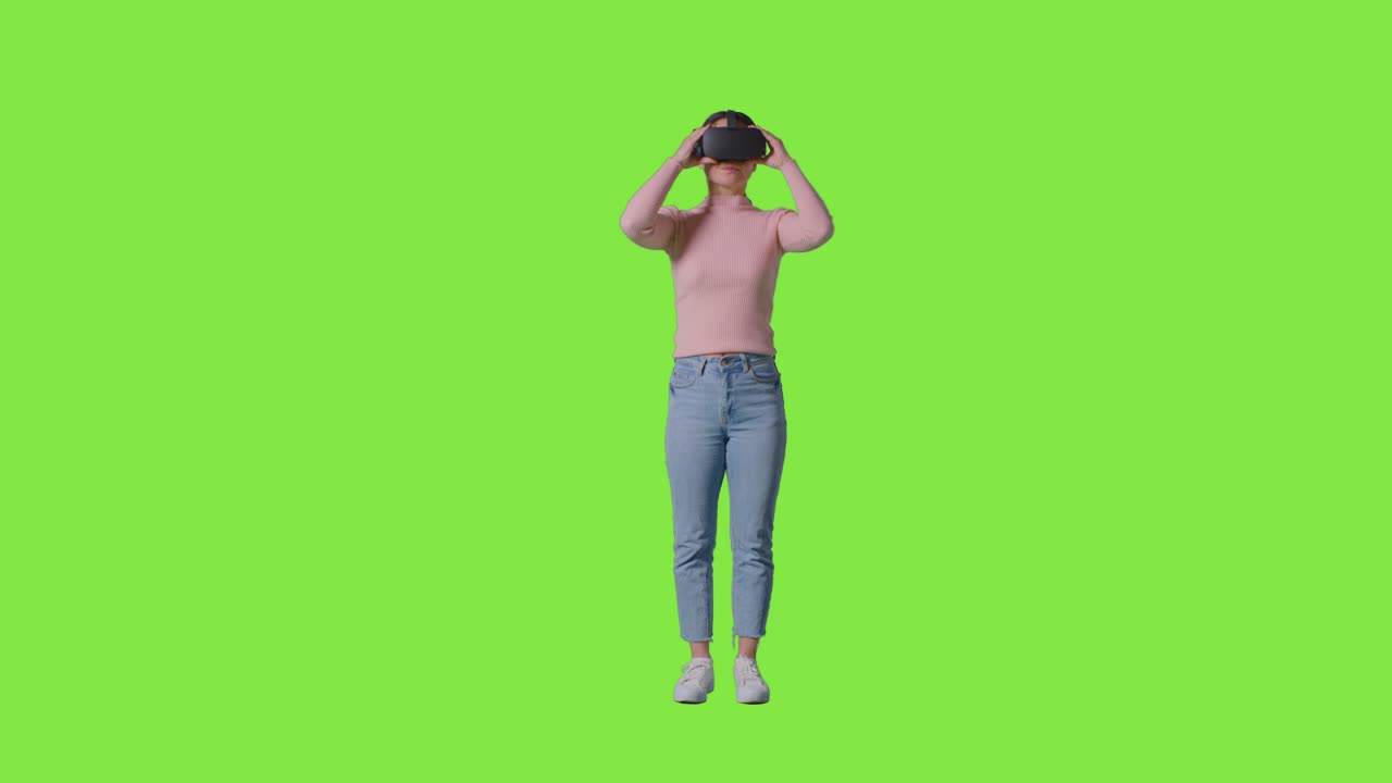 Full Length Shot Of Woman Wearing Virtual Reality Headset And Interacting Against Green Screen Studio Background
