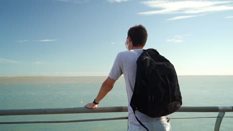 contemplative man with backpack looking at ocean