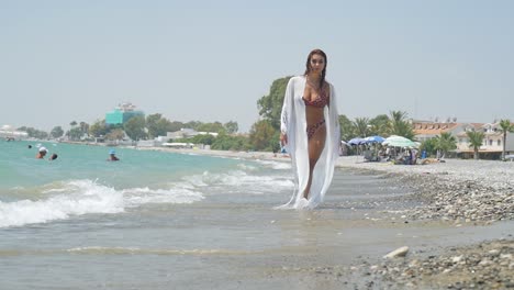 Impresionante-Mujer-Morena-En-Bikini-Con-Estampado-De-Guepardo-Caminando-Hacia-La-Cámara-En-La-Playa-Mientras-Las-Olas-Chocan