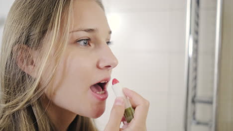 mujer aplicando lápiz labial en el baño