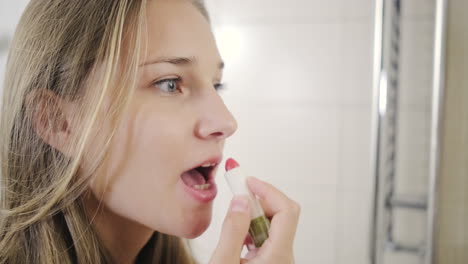 woman applying lipstick in bathroom