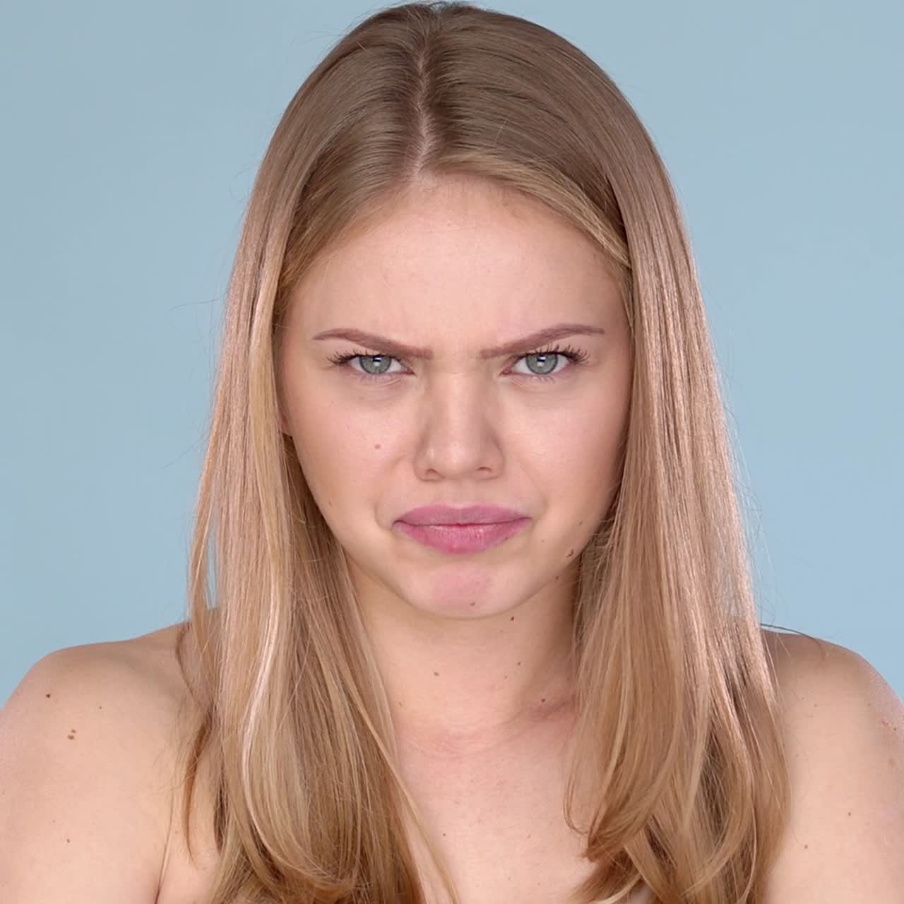 Angry young female  blond hair with bare shoulders  Frustrated emotions on her face
