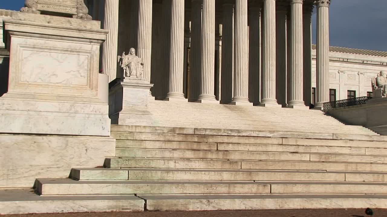 la cálida luz del sol brilla sobre los escalones de piedra blanca y los pilares blancos brillantes de la entrada del edificio de la corte suprema de estados unidos