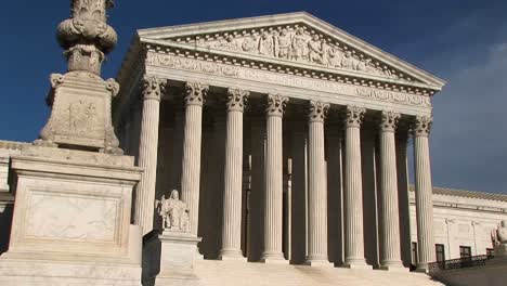 warm sunlight shines on the white stone steps and bright white pillars of the us supreme court building entrance