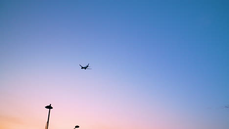 silhouette of an airplane flying against blue sky - low angle