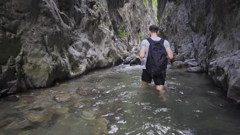 un joven caminando en un arroyo que fluye dentro del cañón.