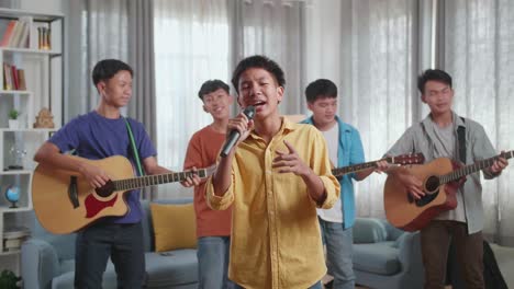 group of young asian friends singing and playing musical instruments at home