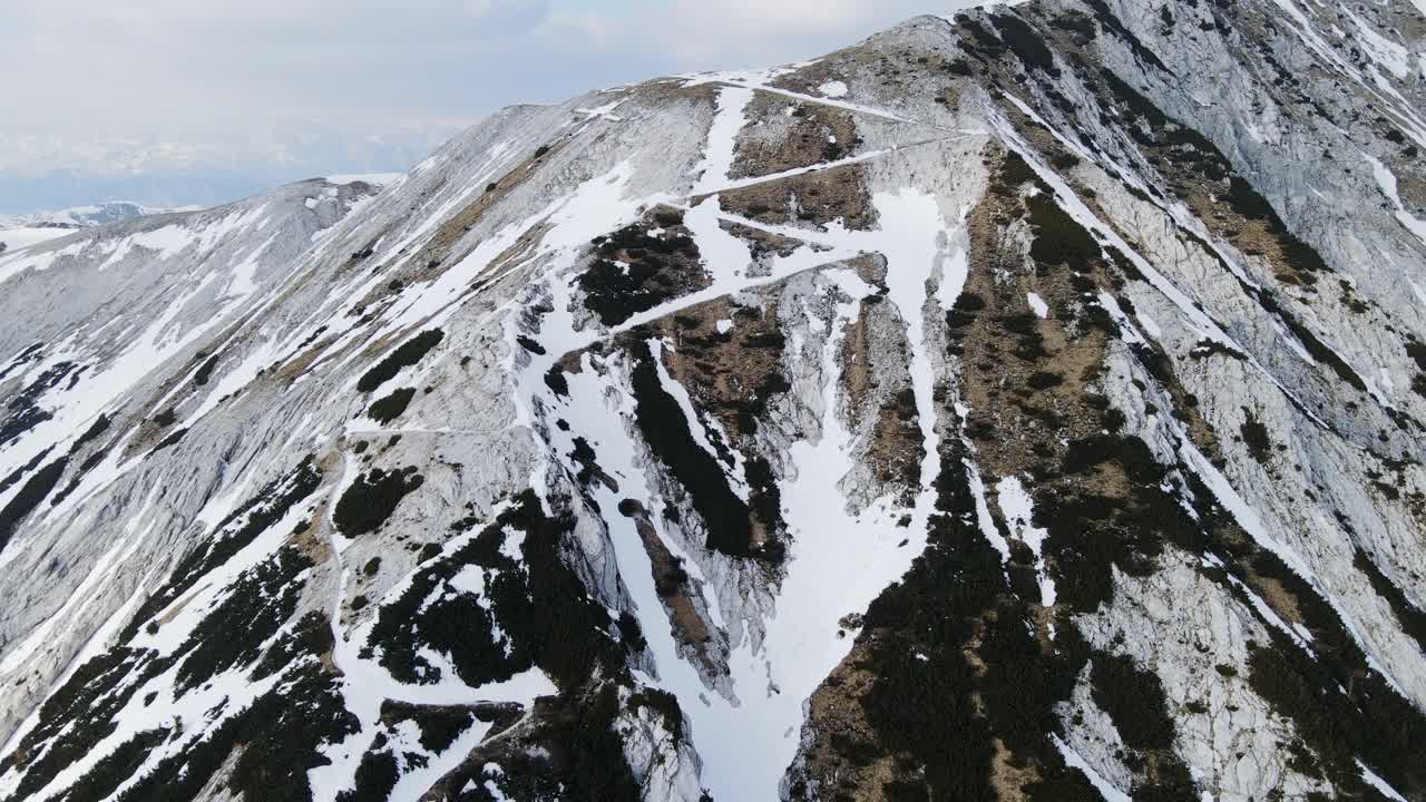 Engebeli dağa doğru kıvrılarak yükselen Veliki Raskovec yürüyüş parkurunun karlı ilkbaharı.