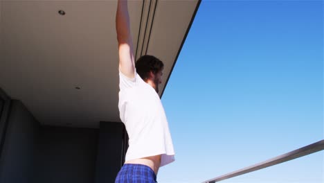 man stretching his arms in balcony