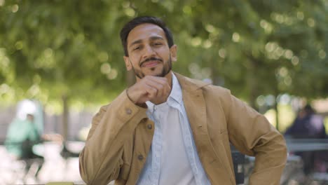 Portrait-Of-Smiling-Muslim-Man-Sitting-At-Outdoor-Table-On-City-Street-1