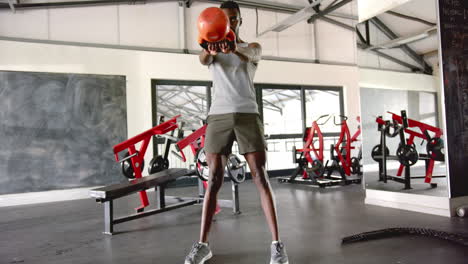 lifting kettlebell, african american man working out in gym, focusing on strength training