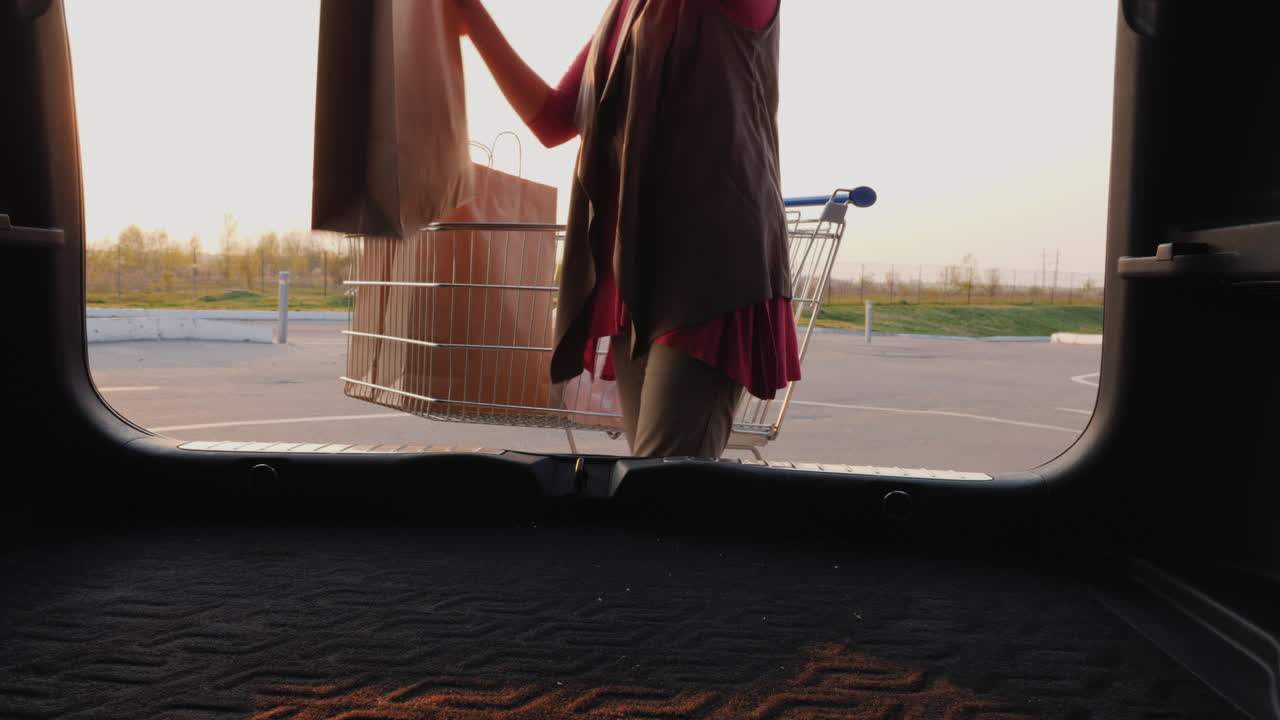 mujer pone bolsas de compras en el maletero de un coche