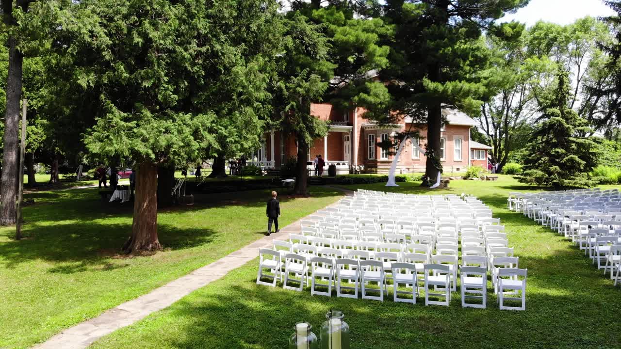Drone flyover of an empty outdoor wedding as the young ring bearer practices walking down the aisle.  This outdoor wedding is located in Nevada, Iowa.