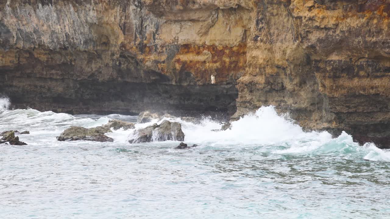 Dynamic ocean waves crash against rugged cliffs at Port Campbell, Australia. Overcast lighting enhances the dramatic coastal scenery