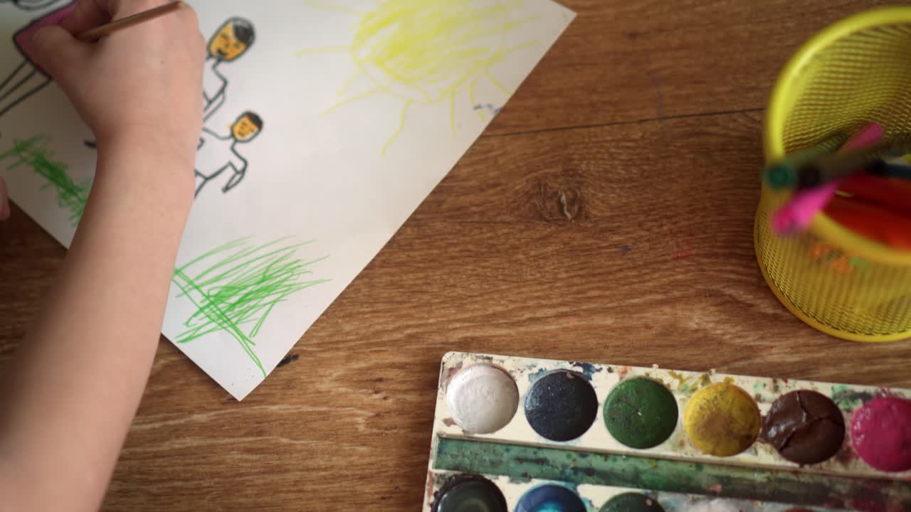 Uma criança no chão desenha com aquarelas 05