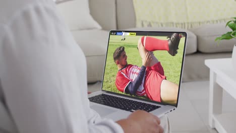 Video-Eines-Kaukasischen-Mannes,-Der-Auf-Dem-Sofa-Sitzt-Und-Zu-Hause-Auf-Dem-Laptop-Fußball-Schaut