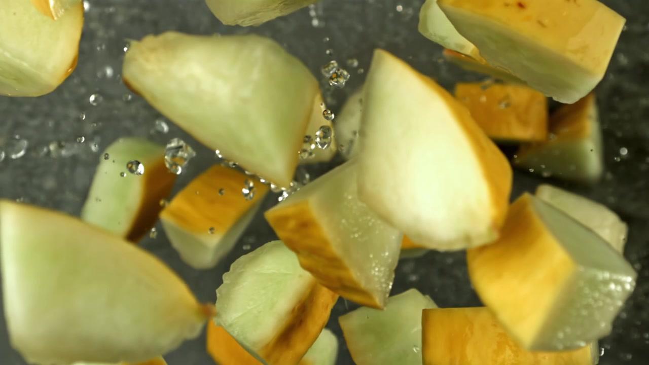 Fresh Melon Pieces Splashing and Floating in Water