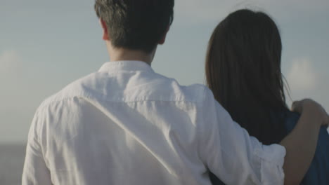 back shot of happy young asian coupe walking by the ocean in the daytime with beautiful sunshine