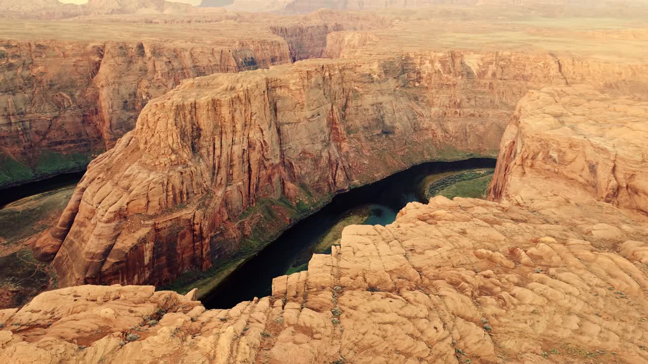 Złote światło rozświetla ściany kanionu, gdy dron oddala się od zakola Horseshoe Bend.