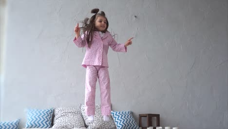 happy little girl jumping on bed