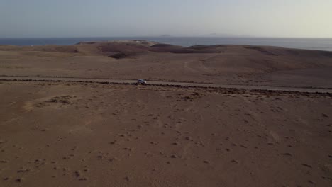 Aerial-shot-of-car-riding-on-the-desert-path