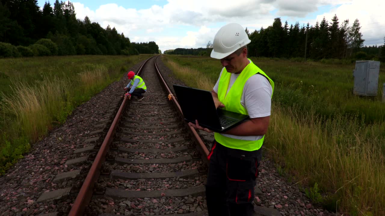 ingeniero cansado en el ferrocarril con una computadora portátil