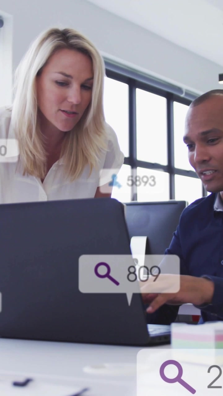 Vertical video: Woman speaking, man gesturing and typing, reviewing office floating search badges
