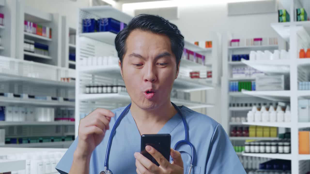 스마트폰을 사용하고 약국에 서서 와우라고 말하는 스테토스코프를 가진 아시아 남성 의사의 클로즈업