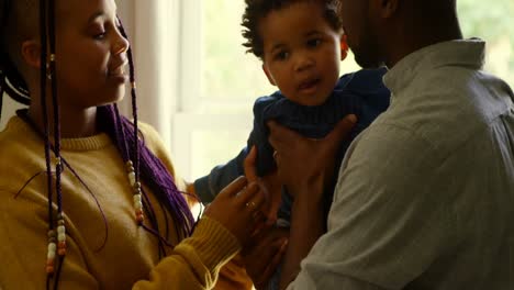 Side-view-of-young-black-parents-holding-their-baby-in-a-comfortable-home-4k