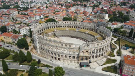 Toma-Aérea-Giratoria-Del-Edificio-Del-Coliseo-O-Del-Anfiteatro-Pula-Arena-Croatia,-Que-Es-Un-Popular-Lugar-Turístico-Histórico-Rodeado-De-Edificios-En-Un-Día-Soleado