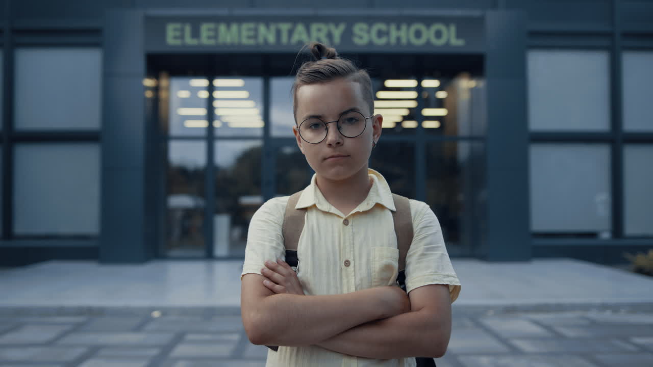 un adolescente serio de pie en la entrada de la escuela de cerca. una cámara que mira a un adolescente.
