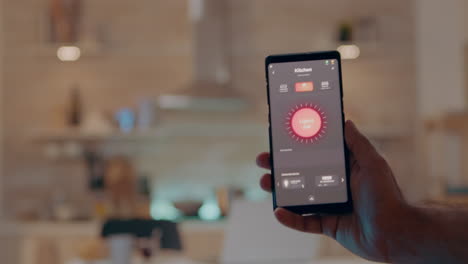 Primer-Plano-De-La-Mano-Del-Hombre-Que-Sostiene-El-Teléfono-Con-Un-Moderno-Software-Que-Controla-Las-Luces