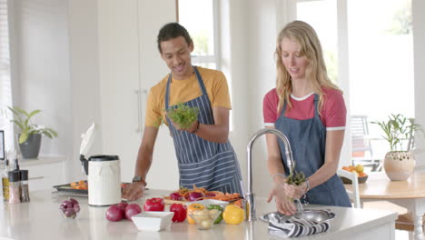 Feliz-Pareja-Diversa-Cocinando-Y-Tirando-Residuos-En-La-Cocina,-Cámara-Lenta