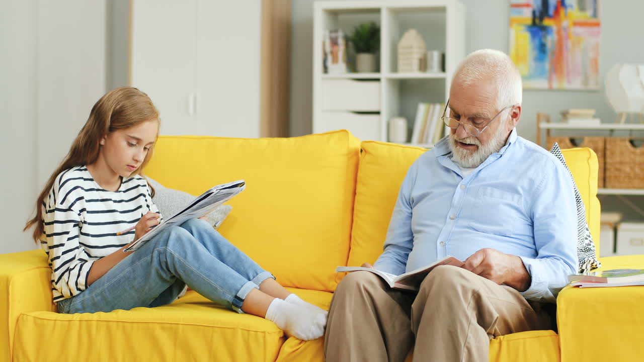 검은 머리 남자가 소파에 앉아 책을 읽는다