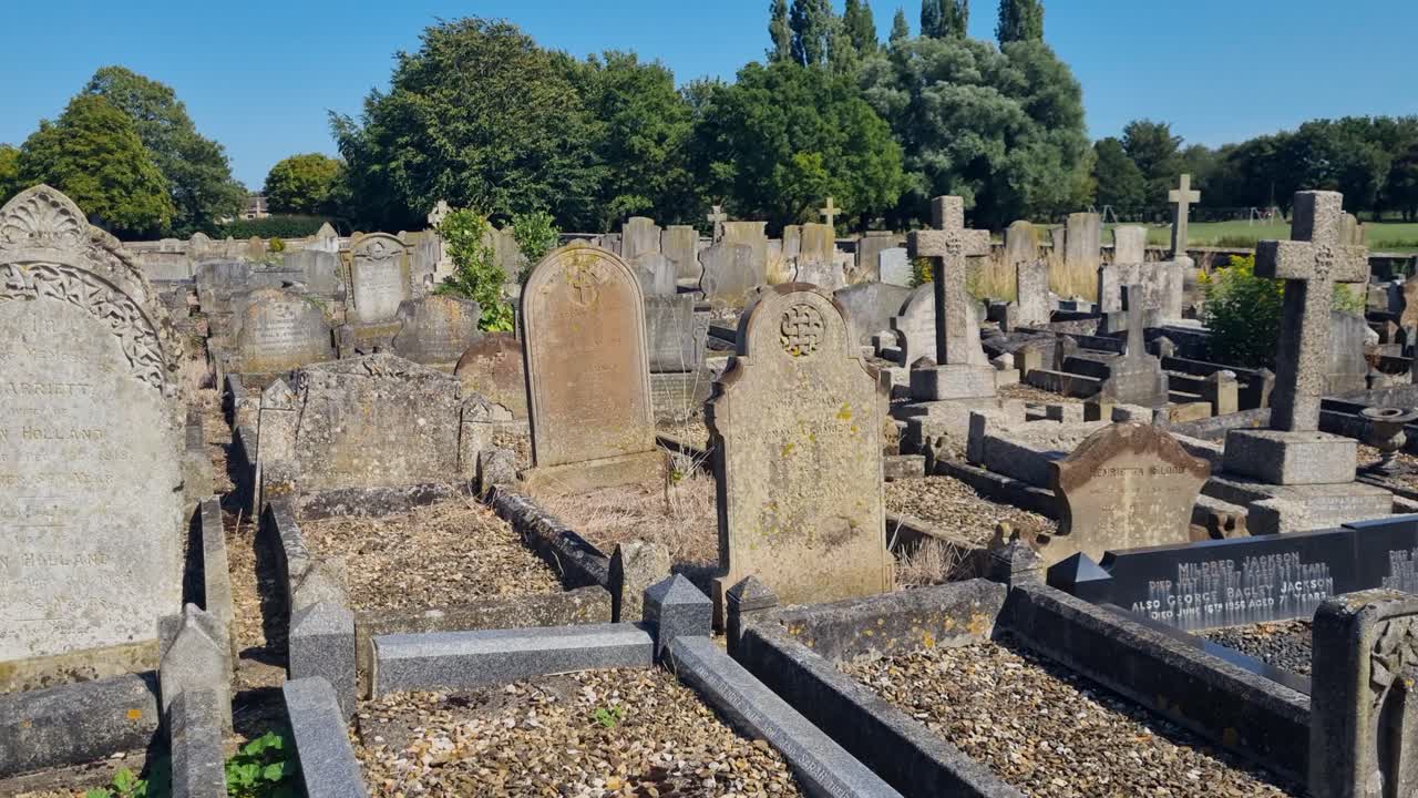 Shot over old tombstones at historic Crowland Abbey, Lincolnshire, England, on a sunny summer day, showcasing medieval gravestones and peaceful churchyard scenery