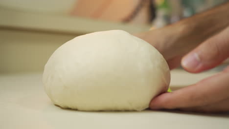 baker shaping and sliding silky smooth bread dough over the counter