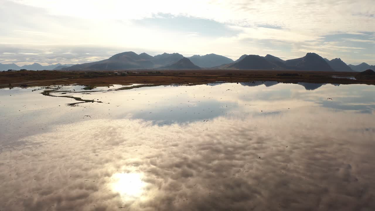 Calm reflection of mountains and sky over water in Vestarelen, Norway