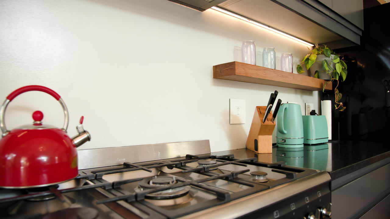 Moderne keuken met rode waterkoker op het fornuis, kruiden en turquoise apparaten, thuis.
