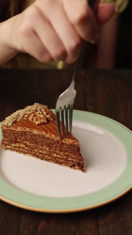 woman eating a slice of layered cake with walnuts