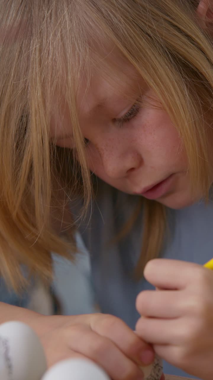 Primo piano di una bambina che decora un uovo di Pasqua con una matita