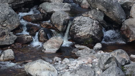 Water-flows-down-a-rocky-mountain-stream-between-boulders-and-rocks