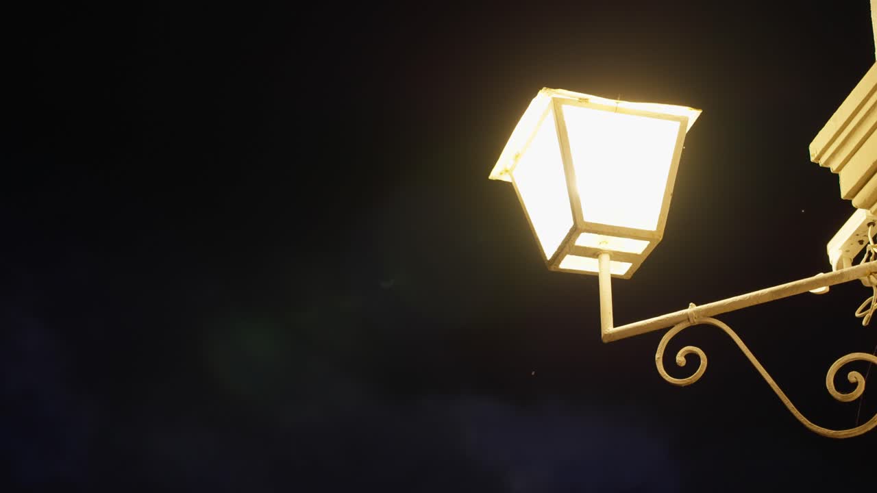 Classic old style lamp or lantern illuminating and glowing in dark night. Street lamp or house lighting fixture illuminated with yellow warm light. Entrance to an old house in European town or village