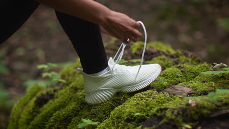woman tying shoes in forest