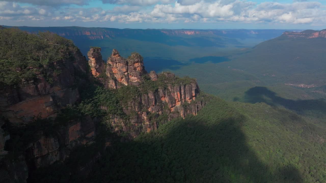drone aéreo sobre tres hermanas montañas azules katoomba sydney nsw australia punto de eco mirador acantilado caminar patrimonio mundial parque nacional árbol de goma de eucalipto bosque azulado día soleado nubes hacia adelante