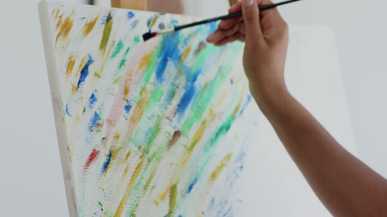Donna in studio che mescola il blu con un pennello, dipingendo segni diagonali per riempire la tela, con spazio per il testo