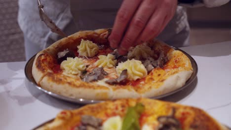 chef decorates freshly baked pizza on kitchen table in restaurant