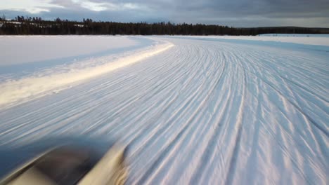 cheap sport cars driving on frozen lake in finland during golden hour – aerial winter landscape with a frozen race track low altitude