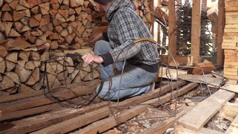 stacking firewood in metal basket in shed, young man doing chores